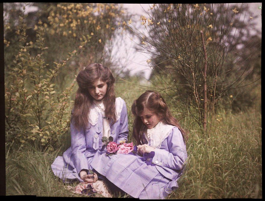شقيقتان تجلسان في حديقة وتقومان بربط باقات من الأزهار، من سنة 1911