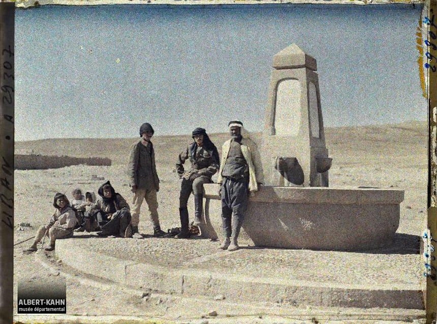 مجموعة من الأشخاص جالسون حول نافورة مياة بالقرب من قرية مجدل عنجر في لبنان سنة 1921.